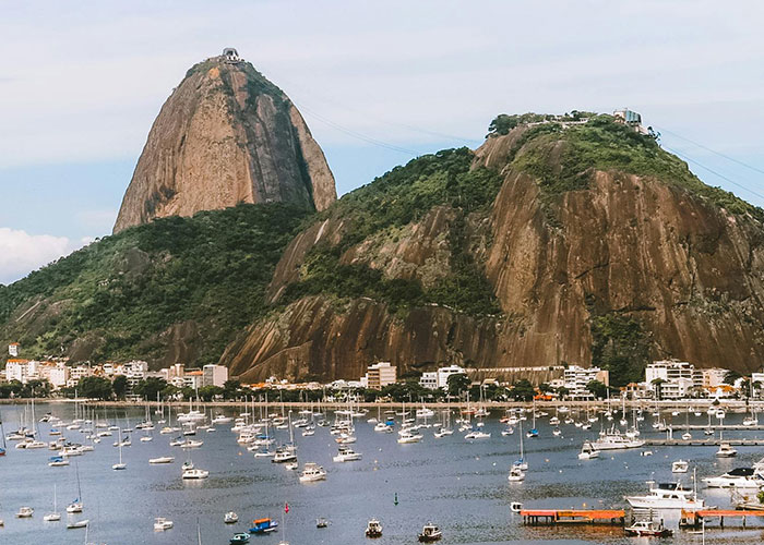 Harbor with many boats below large rocky hills and buildings, illustrating worst cities worldwide you should never visit.