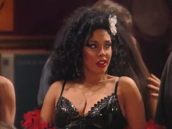 Actress in black dress with flower in hair, related to fake plastic surgeon and botched silicone injections case.