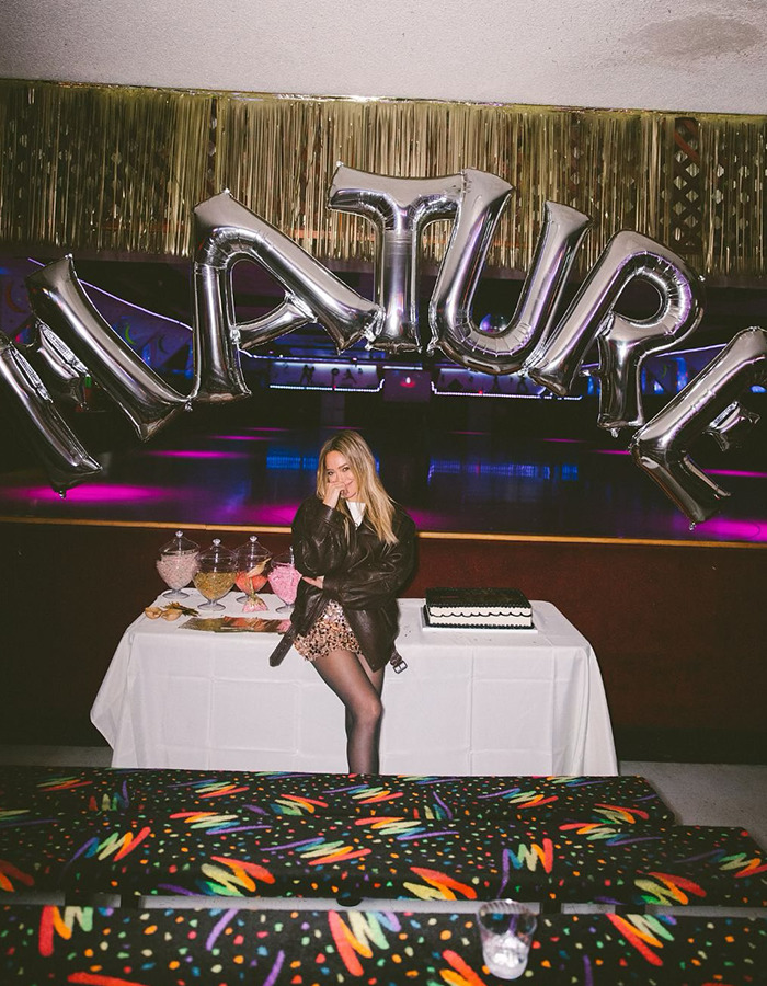 Hilary Duff standing under silver nature balloons with party table, highlighting renewed outrage over 2000s age-gap relationship.