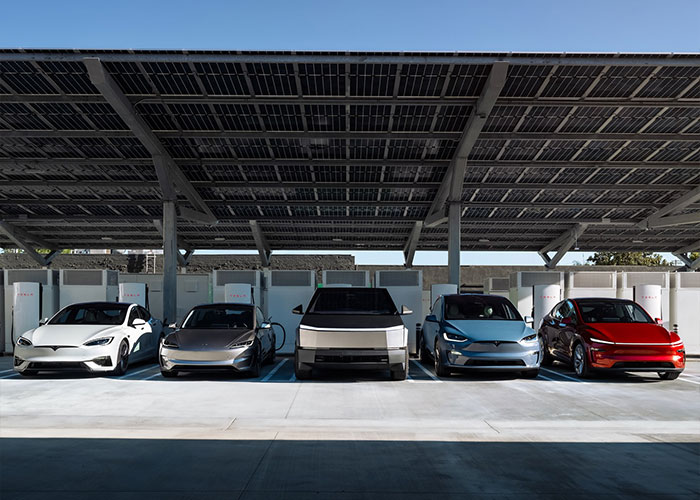 Five electric cars parked under solar panel canopy at a charging station related to Elon Musk electric vehicles.