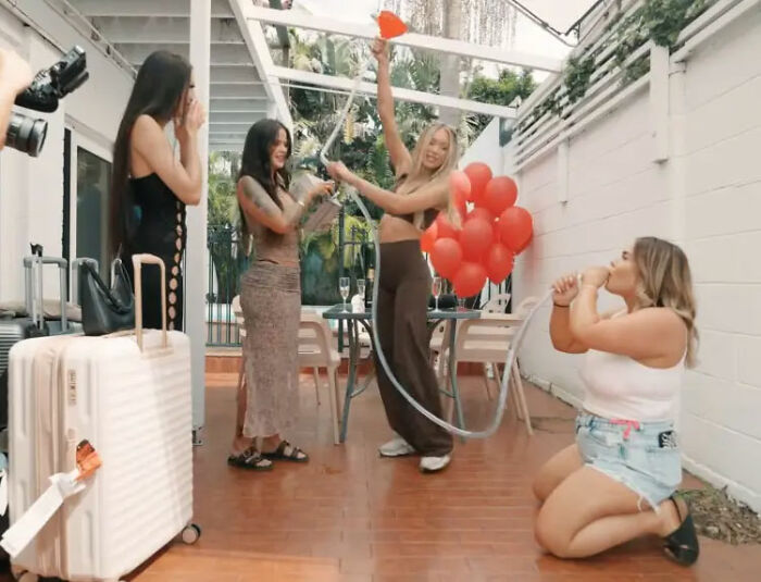 Group of women celebrating outdoors with red balloons and drinks, representing adult content creator lifestyle.