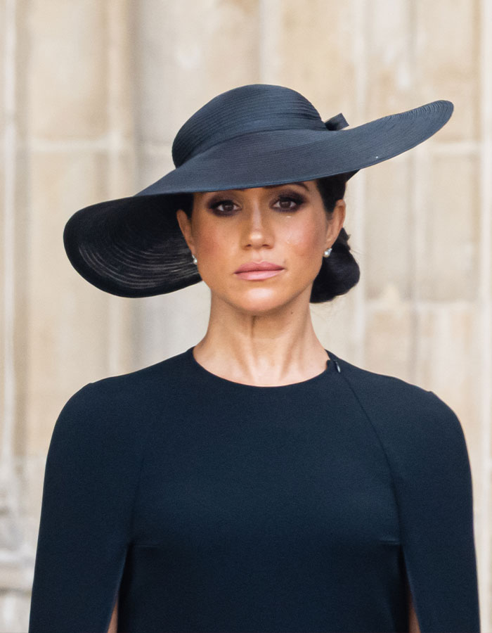 Meghan Markle in a black wide-brim hat and dress, capturing a striking Harper&rsquo;s Bazaar moment that sparked internet buzz.