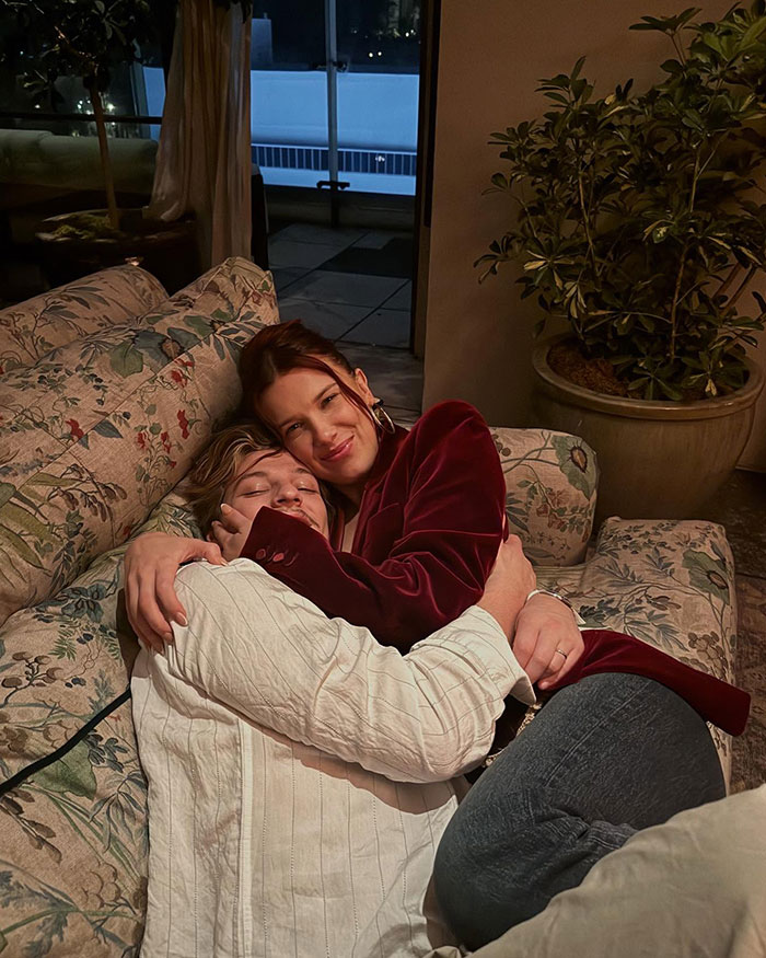 Two people hugging on a floral couch at night, related to Millie Bobby Brown name change news and fan reactions.