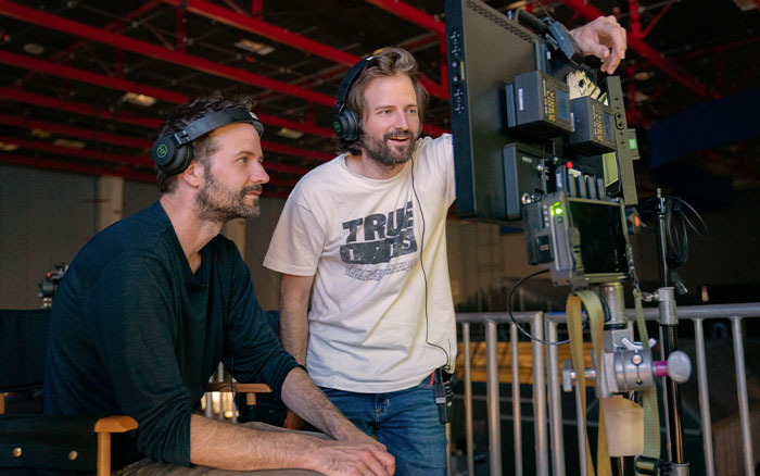 Stranger Things creators on set wearing headsets, reviewing footage on monitor while preparing for final episodes.