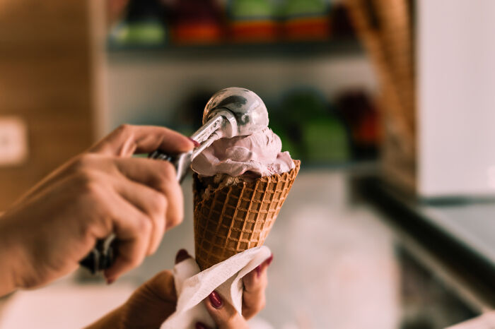 Person scooping ice cream into a waffle cone, illustrating stories of lessons learned from mistakes and never again moments.