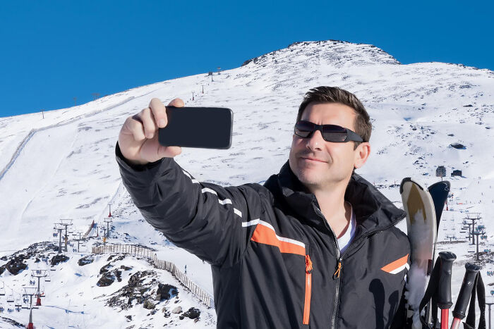 Man in sunglasses taking a selfie with skis on a snowy mountain, representing people who disappeared to start new lives.
