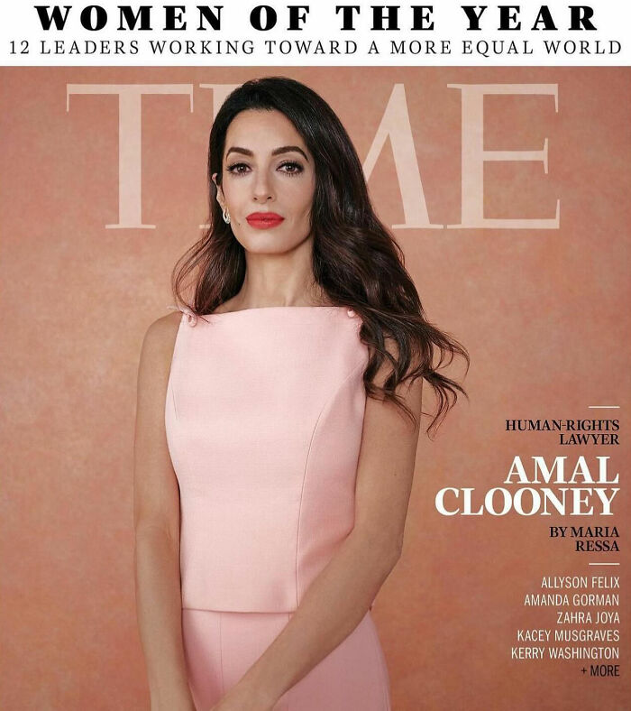 Amal Clooney on magazine cover wearing pink dress with styled hair and red lipstick in a polished portrait setting.
