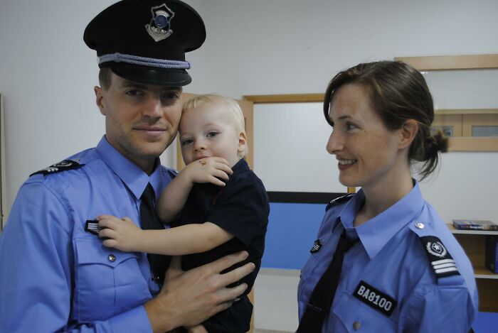 Police officers in uniform with a young child, related to father and son zip-lining incident during vacation.