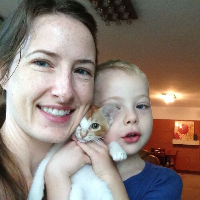 Woman and young boy holding a kitten indoors, illustrating father and son in tragic zip-lining incident during vacation.