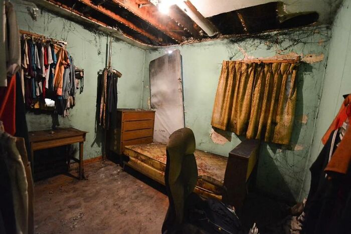 Dilapidated Zillow home interior with old furniture, peeling walls, and exposed ceiling beams in a neglected room.