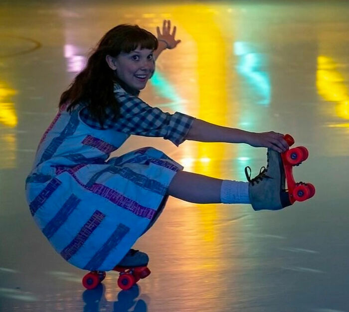 Actress from Stranger Things roller skating indoors, highlighting bullying issues involving Millie Bobby Brown.