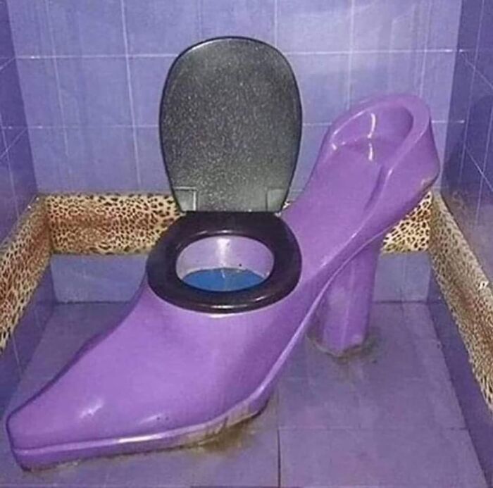 Purple high heel shaped toilet with black seat in a bathroom featuring blue tiles and leopard print border trim.
