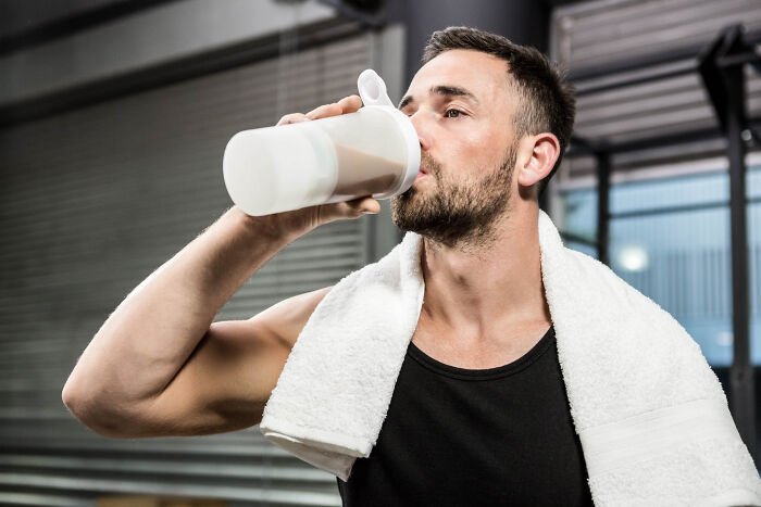 Man in gym with a towel drinking from a bottle, illustrating stories of little lies that backfired hard on people.