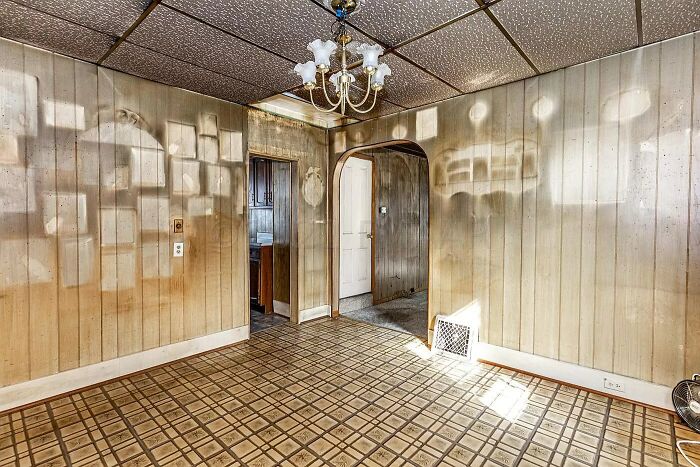 Faded vintage dining room with patterned linoleum floor and wood panel walls in a Zillow home listing to keep an open mind