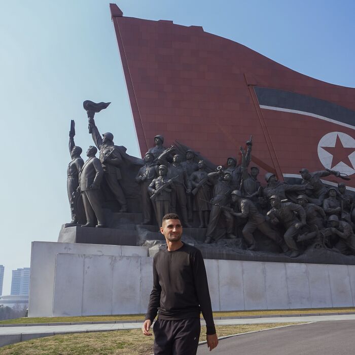 American travel influencer standing near a large monument in North Korea during his marathon experience.