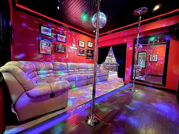 Colorful dance room with leather couch, disco ball, and poles in a unique Zillow home to see and believe.