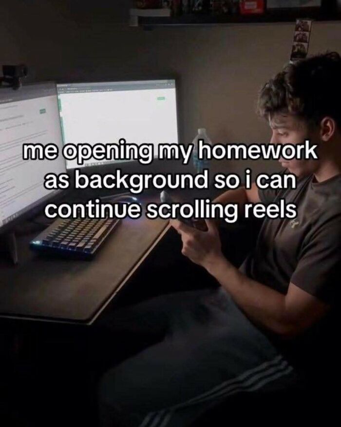 Teen focused on phone with homework open on computer screen, illustrating hilarious educational memes about procrastination.