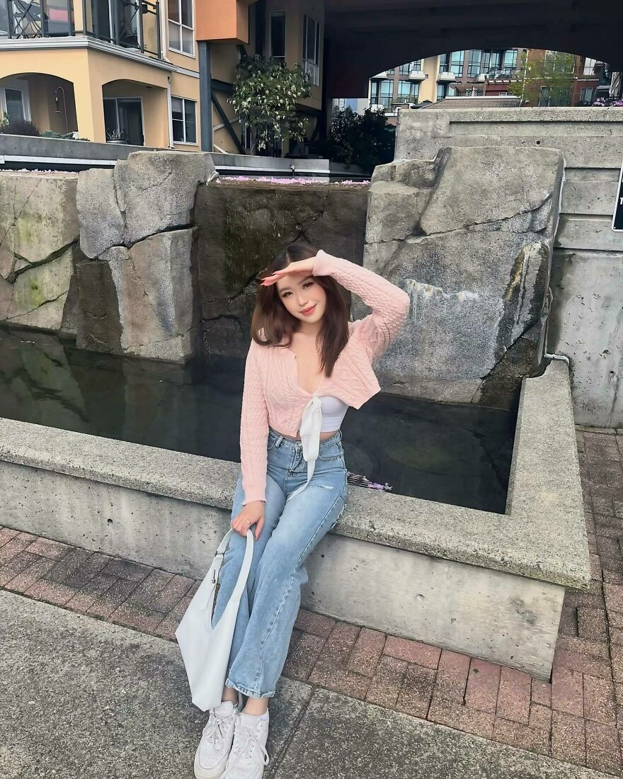Young woman posing outdoors near water feature, symbolizing the rejection of Asian stereotypes in the modern world.