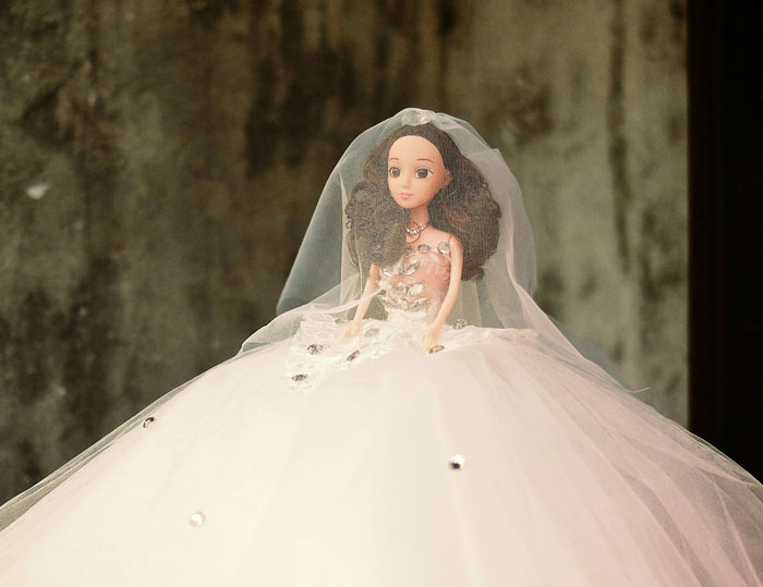 Bride doll wearing detailed white wedding dress and veil, illustrating stories about how some folks don’t deserve nice things.