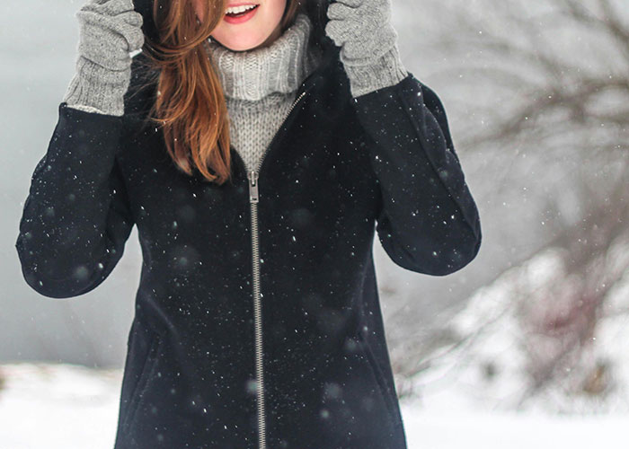 Woman wearing winter coat and gloves standing outside in snow, illustrating common knowledge that seems to blow people’s minds.