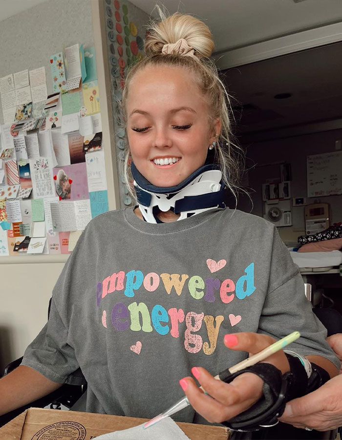 Young girl who was paralyzed at 16 wearing a neck brace and smiling while engaging in creative therapy.