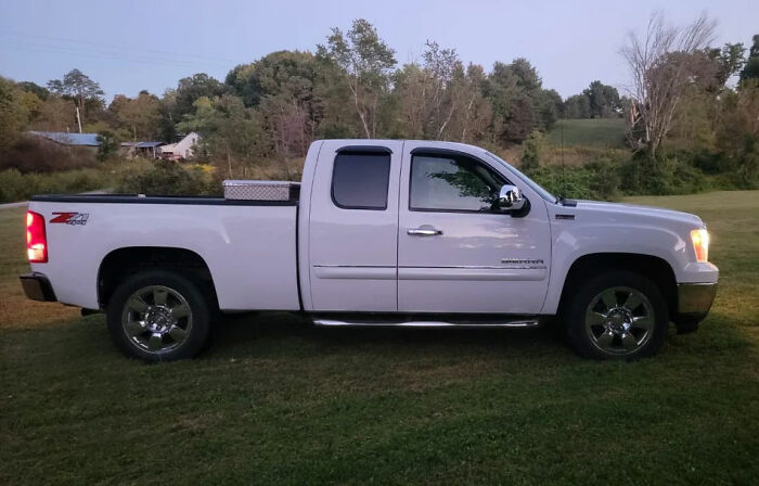 White pickup truck parked on grass near rural area, related to man leaving 2YO daughter in burning car after drunk crash. White pickup truck parked on grass near rural area, related to man leaving 2YO daughter in burning car after drunk crash.