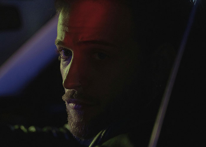 Man with a serious expression in low light, capturing the eerie mood of bizarre events that creep people out.