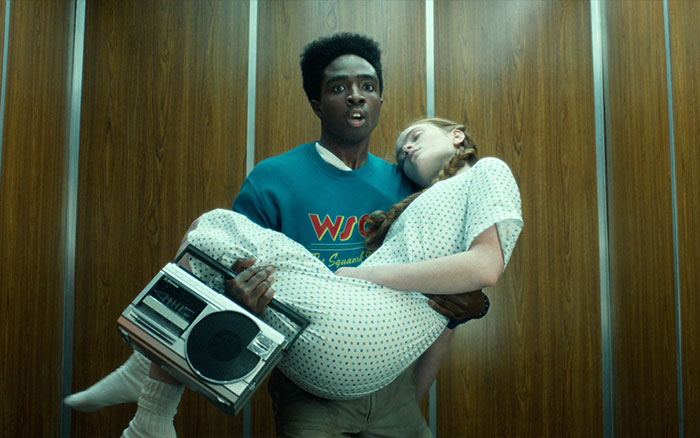 Young man carrying an unconscious girl in elevator, Stranger Things creators issue cryptic warning for fans before final episodes.