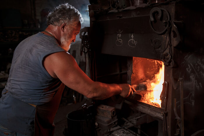 Man stoking a fiery furnace in a workshop, symbolizing the little lie that backfired on him hard.