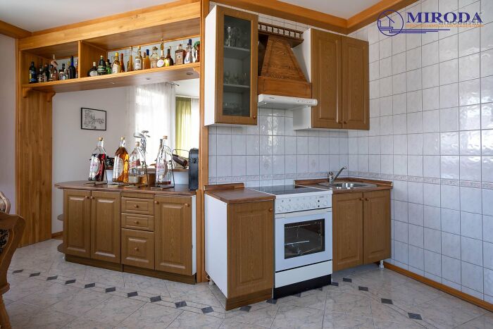 Wooden kitchen cabinets with white tiled walls and a bar area showing real estate listings with unique interior features.