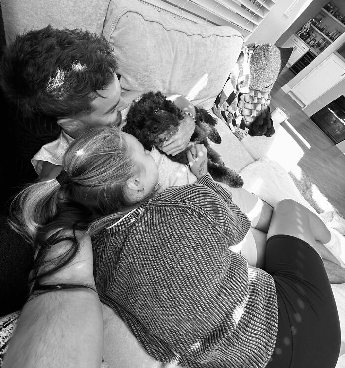 Couple relaxing on a couch with a dog, capturing a candid moment related to JoJo Siwa's fans and Chris Hughes confession.