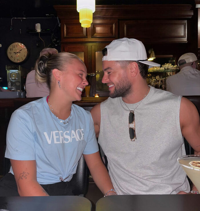 Young couple sharing a joyful moment in a bar, capturing JoJo Siwa's fans stunned reaction to Chris Hughes' reality TV confession.