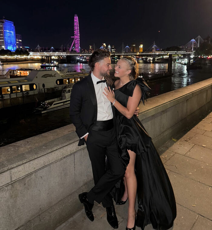 Couple dressed elegantly by riverside at night with London Eye and city lights, referencing JoJo Siwa's fans and Chris Hughes confession.