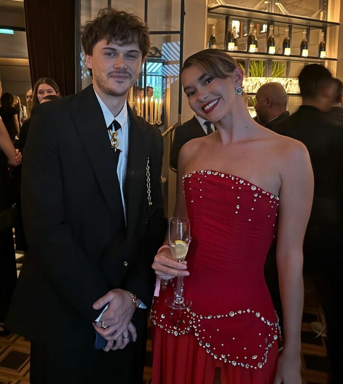 Two well-dressed people at a party, highlighting an influencer criticized for partying with contagious infection. Two well-dressed people at a party, highlighting an influencer criticized for partying with contagious infection.