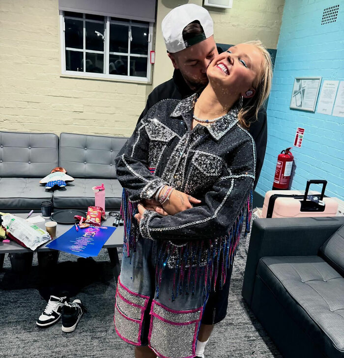 JoJo Siwa smiling and hugging Chris Hughes backstage, fans stunned and confused after his reality TV confession
