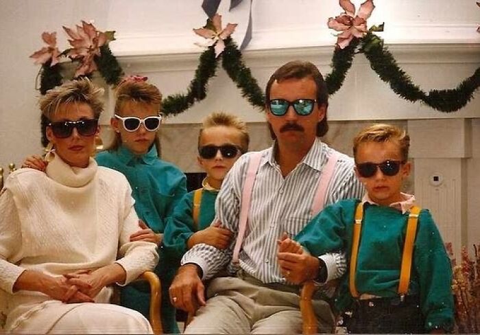 Family posing awkwardly in studio with sunglasses and vintage 80s clothing, showcasing awkward studio pics style.