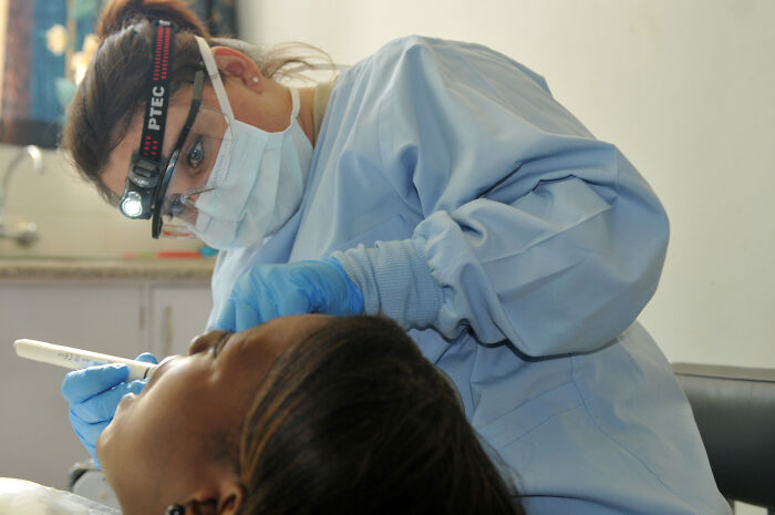 Dentist wearing protective gear examining patient’s teeth, highlighting wildest patient horror stories in dental care.