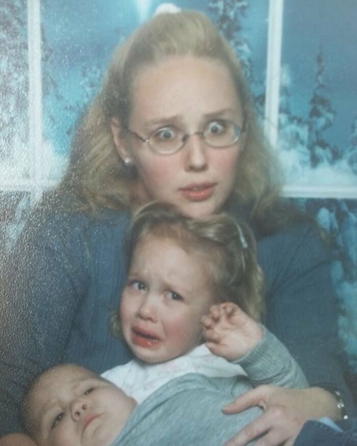 Woman with surprised expression holding two distressed children in a poorly staged awkward studio photo session.