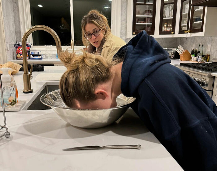 Two women in a kitchen, one with face in a bowl of water, illustrating leaked PR emails about damage control after Christy tanks.