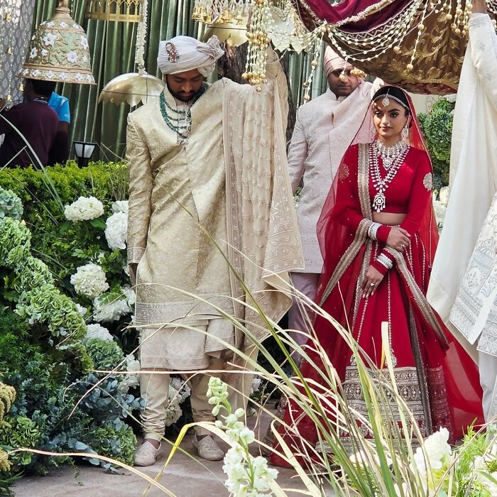 Bride and groom in traditional attire at a lavish wedding, with floral decor and intricate fabric details. Bride and groom in traditional attire at a lavish wedding, with floral decor and intricate fabric details.