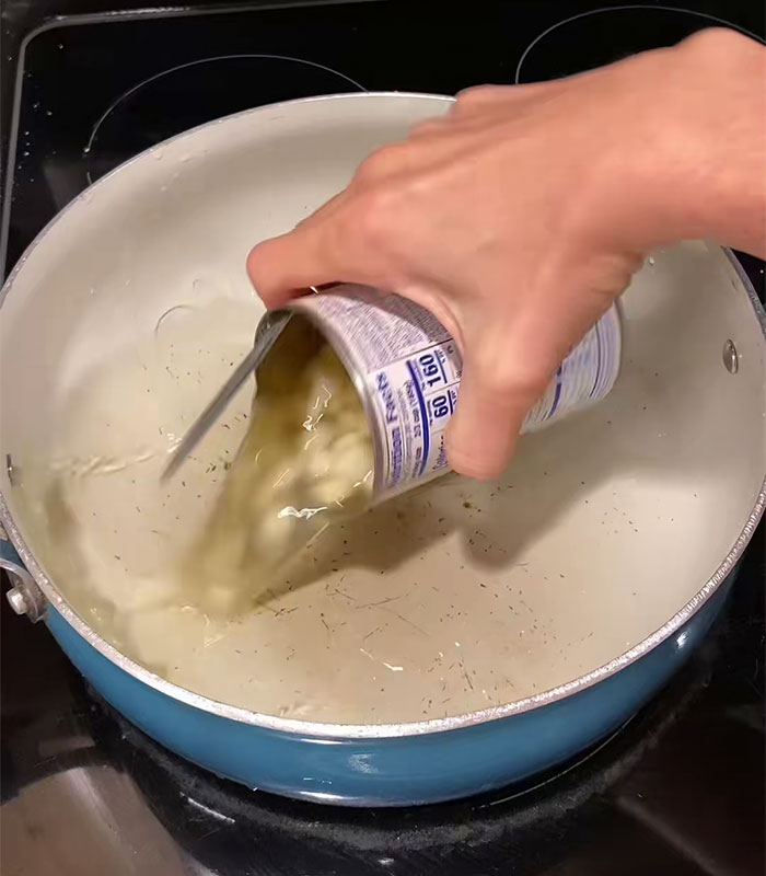 Hand pouring canned food into a large pot showing wild American food creations that shocked the internet. Hand pouring canned food into a large pot showing wild American food creations that shocked the internet.