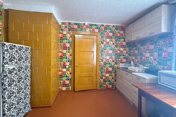 Cocina colorida con azulejos, puerta amarilla y nevera con diseño, parte de listados inmobiliarios entretenidos.