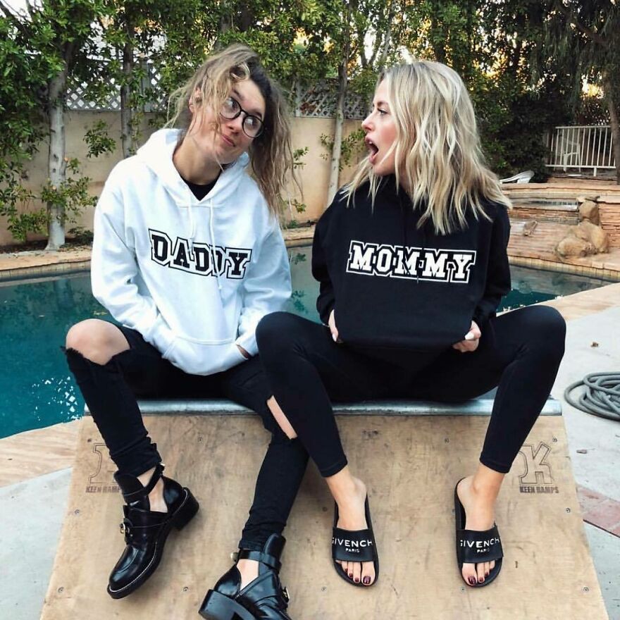 Two women wearing hoodies with daddy and mommy text, sitting by a pool, representing internet fame and Corinna Kopf net worth. Two women wearing hoodies with daddy and mommy text, sitting by a pool, representing internet fame and Corinna Kopf net worth.