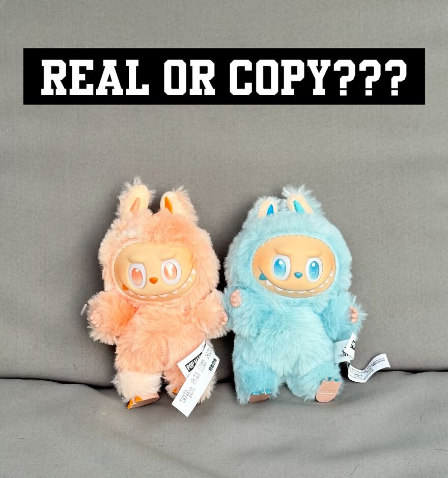 Two furry Labubu dolls, one peach and one blue, displayed with a sign questioning authenticity amid counterfeit concerns.