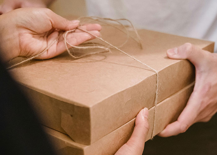 Hands holding and untying string around a brown box, representing fascinating items found in the walls of homes.