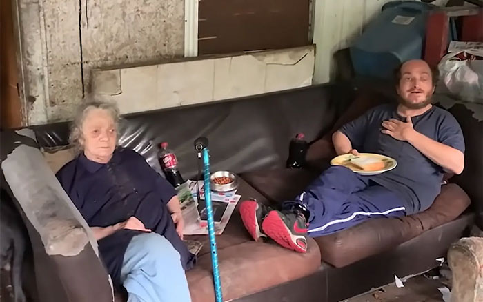 Two people sitting on a worn couch in a cluttered room highlighting America&rsquo;s most inbred family and viral fame impact.