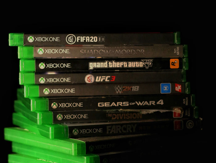 Stack of Xbox One video games including FIFA, Shadow of Mordor, and Grand Theft Auto, illustrating stories of people’s behavior.