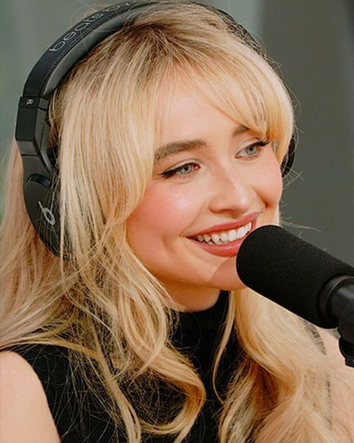 Young woman with blonde hair wearing headphones and speaking into a microphone, related to Taylor Swift friendship shoe choice.