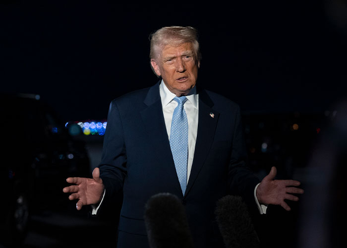 Donald Trump speaking outdoors at night, addressing reporters with microphones in front of him. Donald Trump speaking outdoors at night, addressing reporters with microphones in front of him.