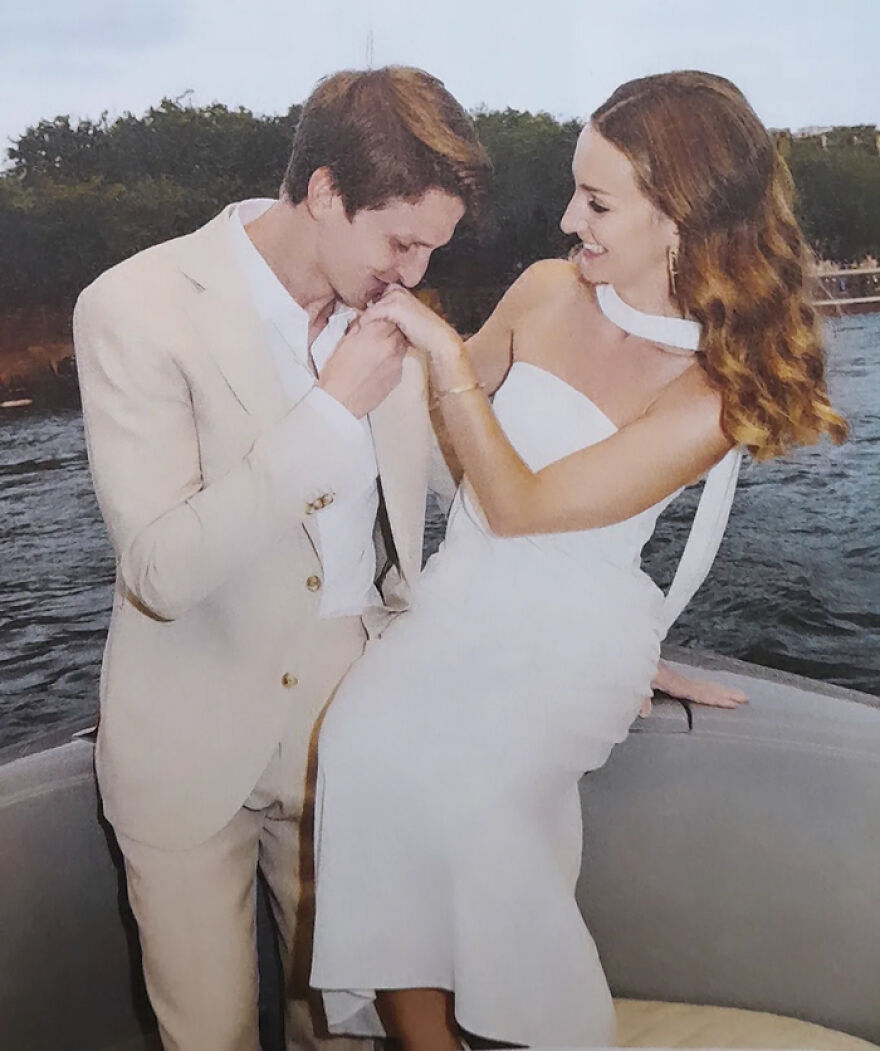Couple sharing a romantic kiss on the hand by the water, illustrating types of kisses in culture and history.